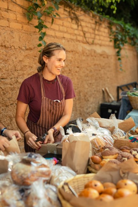 Vendeuse souriante Vendeuse souriante préparant des produits alimentaires sur un marché.