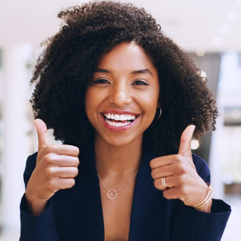 Femme souriante avec des cheveux bouclés, faisant un geste de pouce levé. Femme souriante avec des cheveux bouclés, faisant un geste de pouce levé.