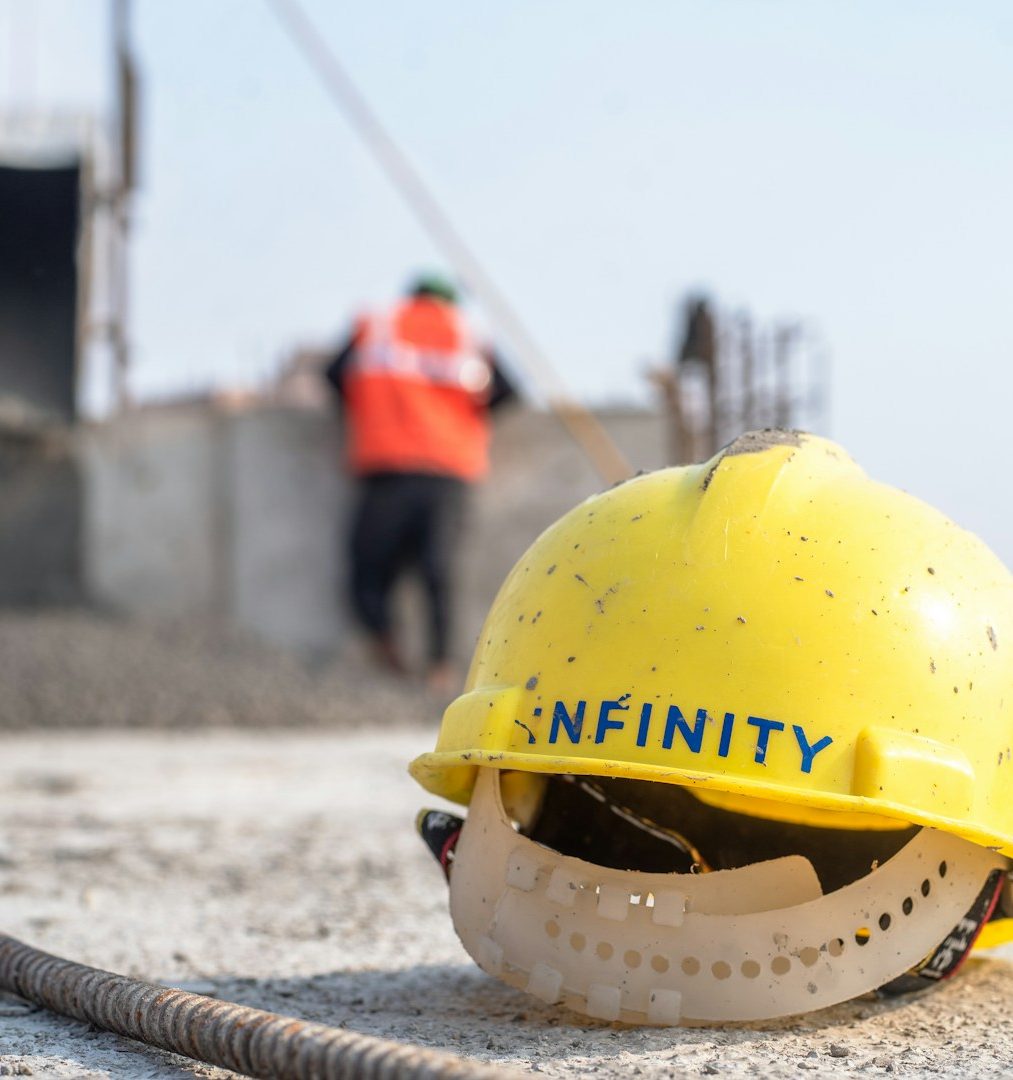 Casque de sécurité jaune au premier plan, avec des ouvriers en arrière-plan sur un chantier. Casque de sécurité jaune au premier plan, avec des ouvriers en arrière-plan sur un chantier.