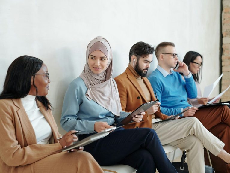 Groupe de personnes assises, échangeant et observant des tablettes et documents. Groupe de personnes assises, échangeant et observant des tablettes et documents.