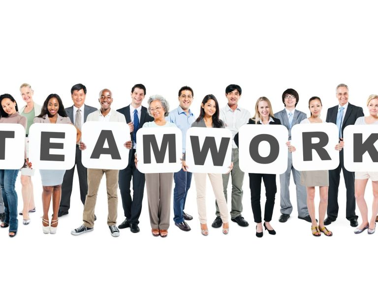 Un groupe divers de personnes tenant des lettres formant le mot "TEAMWORK". Un groupe divers de personnes tenant des lettres formant le mot "TEAMWORK".
