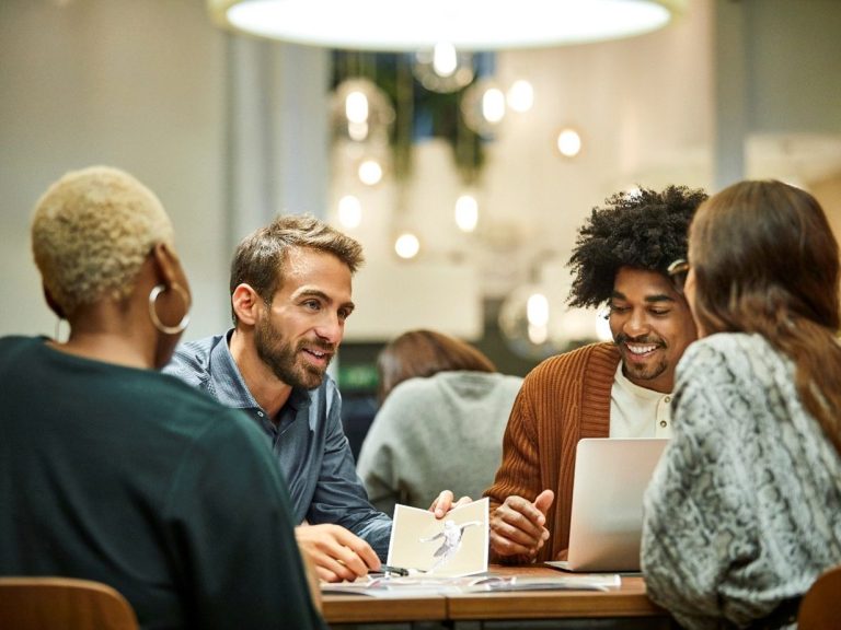 Quatre personnes se rencontrent autour d'une table, discutant et utilisant un ordinateur portable. Quatre personnes se rencontrent autour d'une table, discutant et utilisant un ordinateur portable.