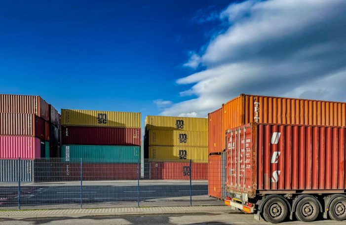 Conteneurs de transport colorés Conteneurs de transport colorés empilés dans un port sous un ciel bleu avec des nuages.